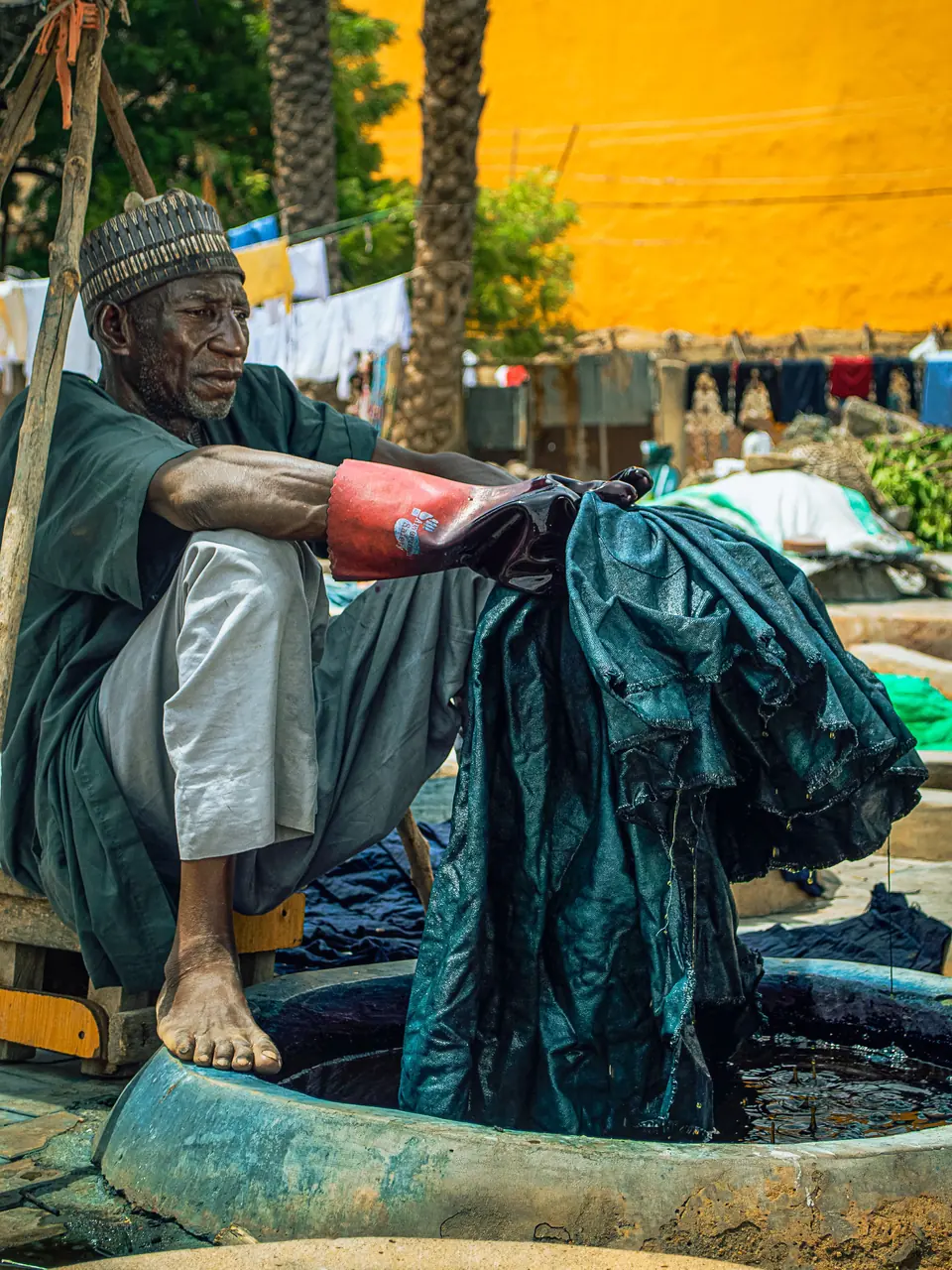 Dyer lifting a fabric out of the indigo vat